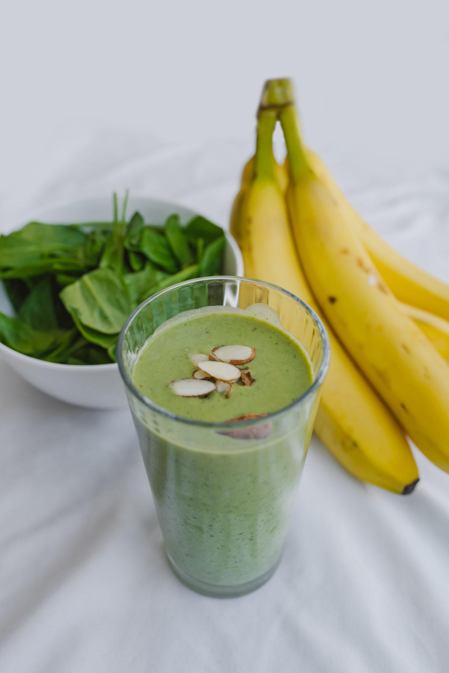 Bunch of bananas, a green smoothie, and a bowl of greens.