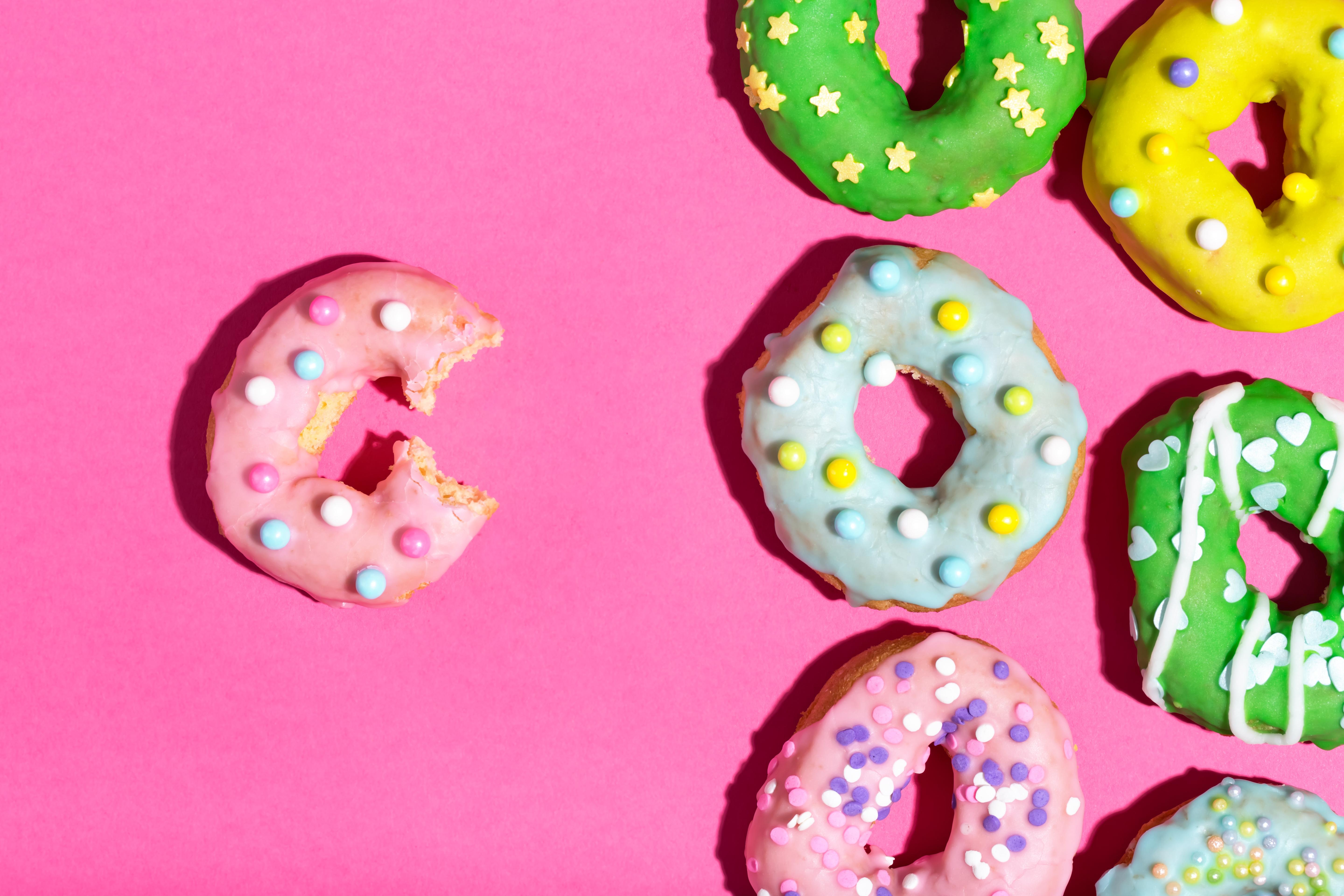 Colorful sprinkled donuts on a pink background