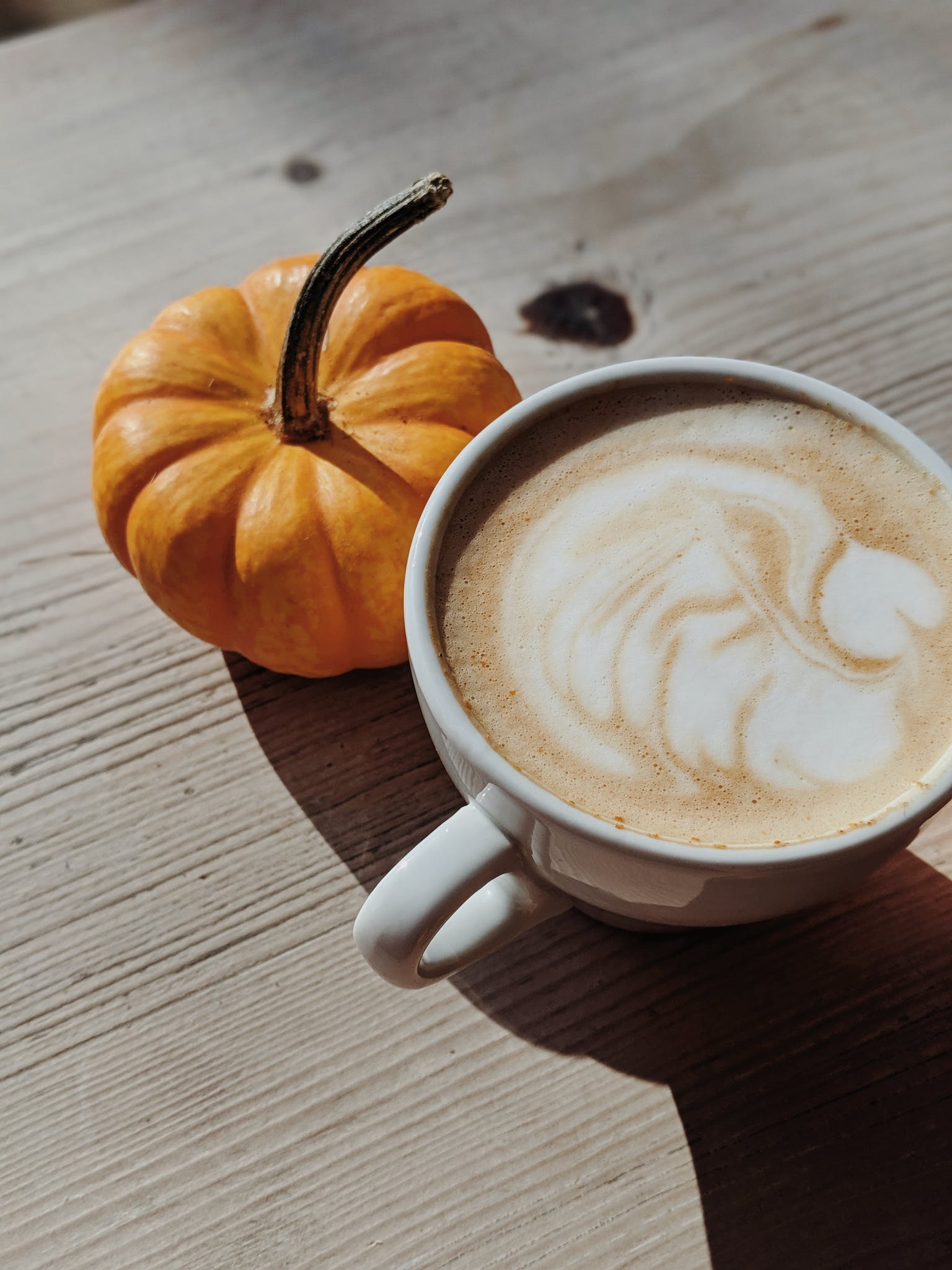A pumpkin and pumpkin spice latte representative of fall seasonal eating.