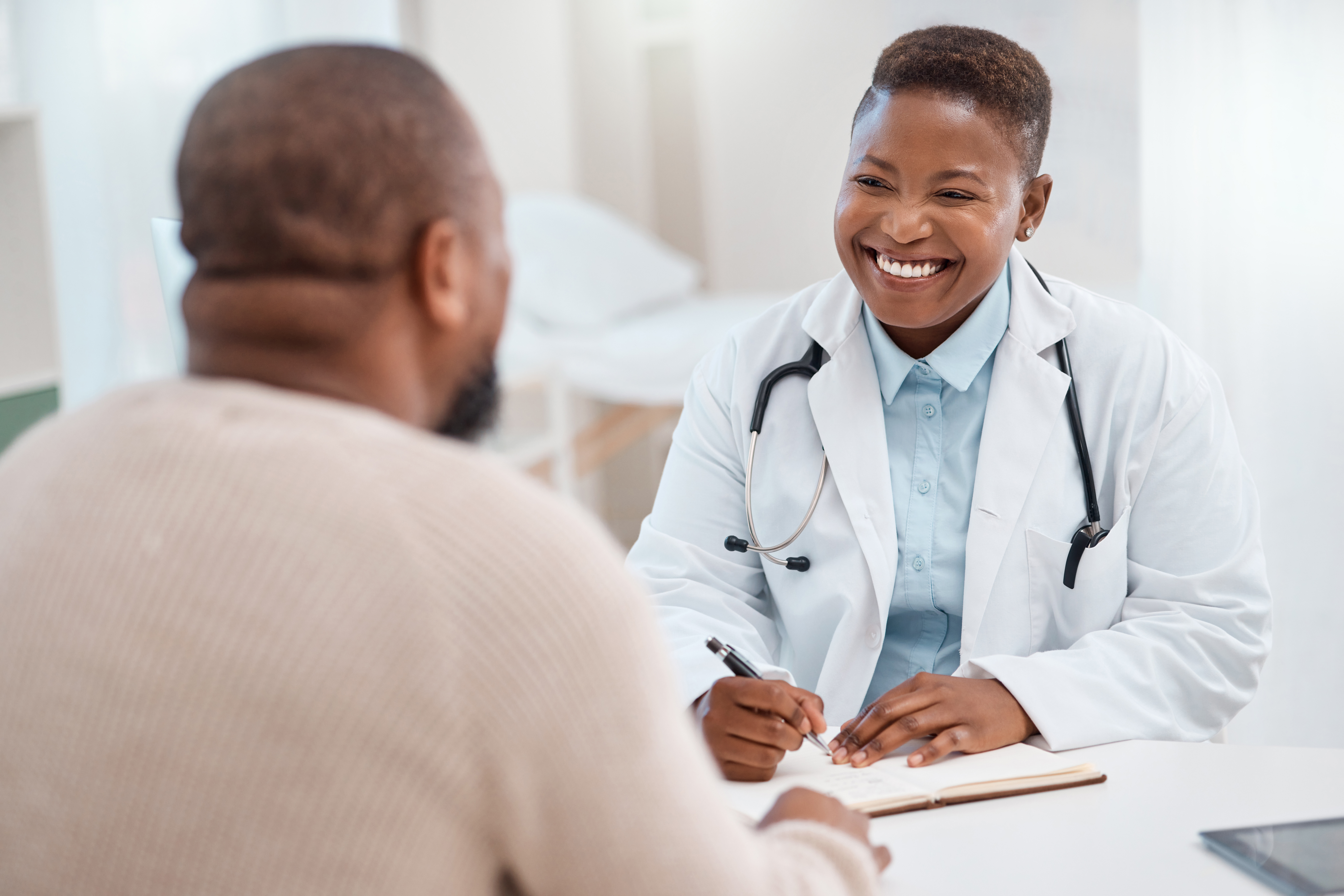 primary care physician in white lab coat smiles at patient