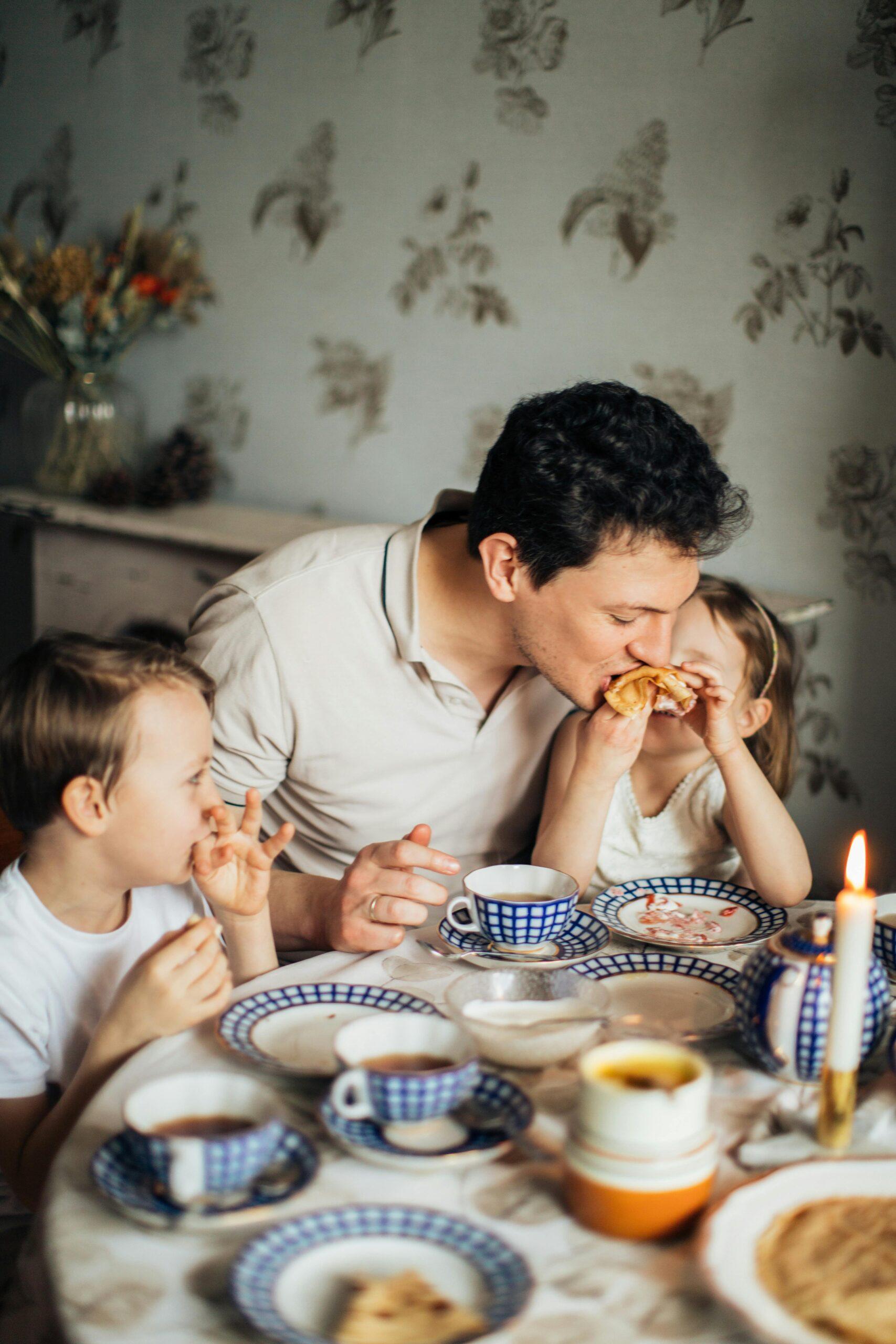man eating with two children at a table full of food
