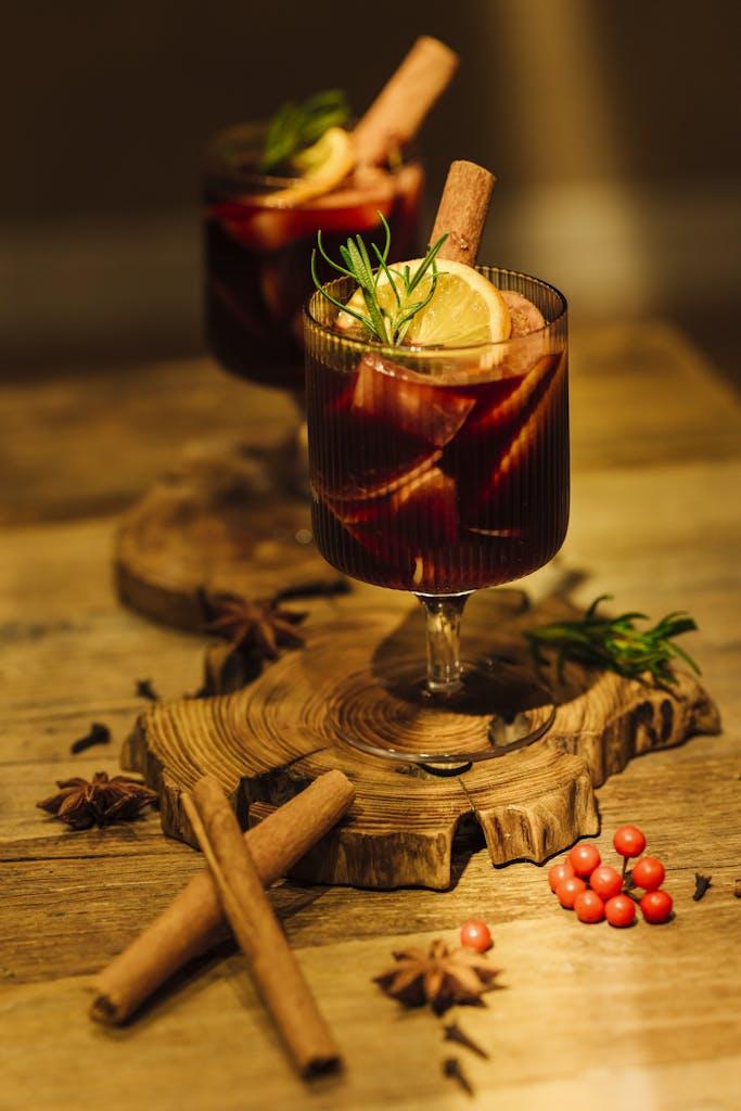 Close-up of festive mulled wine with cinnamon sticks and citrus slices on a wooden tray.