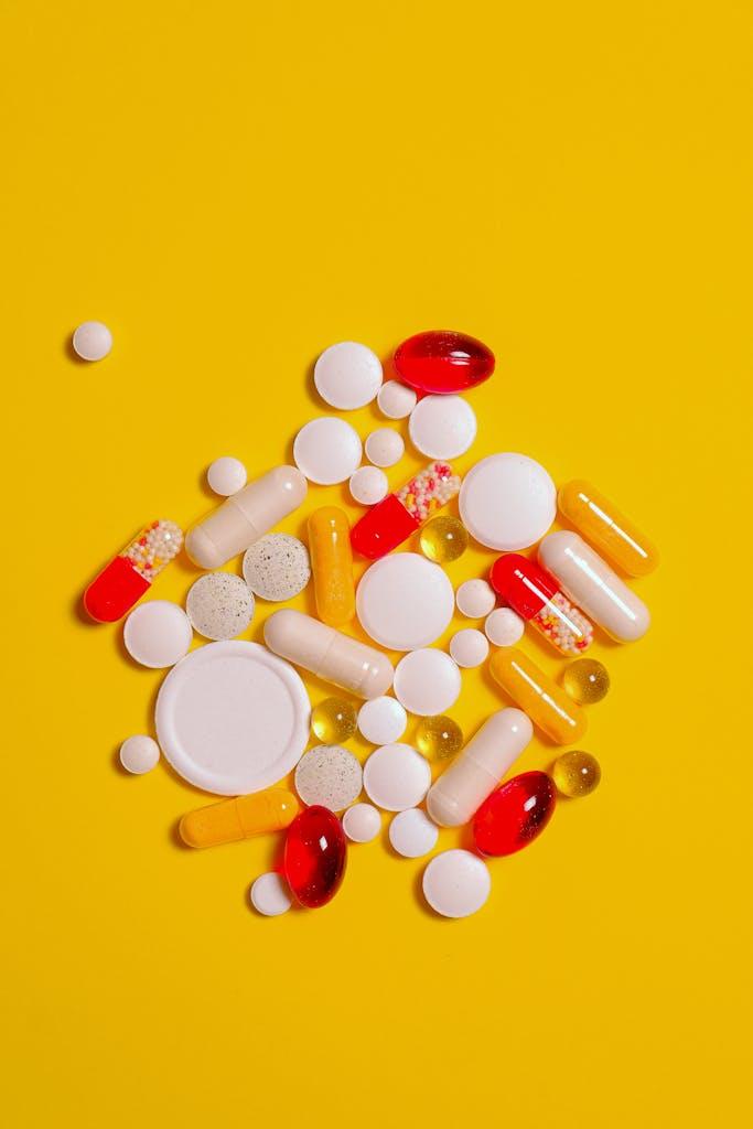 A collection of diverse tablets and capsules on a vibrant yellow background, symbolizing healthcare and medication.