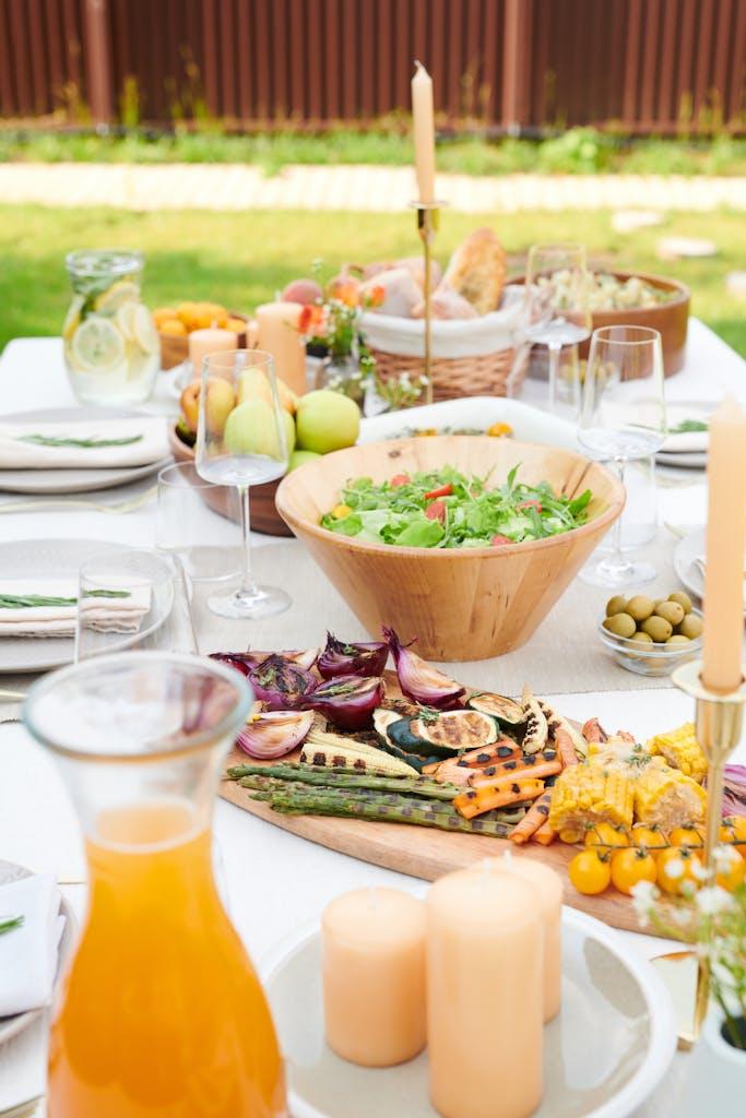 A beautiful outdoor dining setup featuring fresh salads, grilled vegetables, and vibrant fruits.