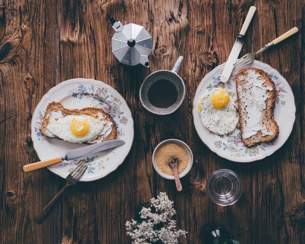 Vintage-style flat lay of breakfast with eggs, toast, and coffee on a wooden table.